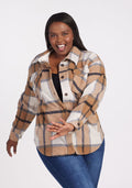 A woman smiles playfully, posing in the Woolx Sawyer Shacket in Camel Plaid over a black top and blue jeans against a plain white background.