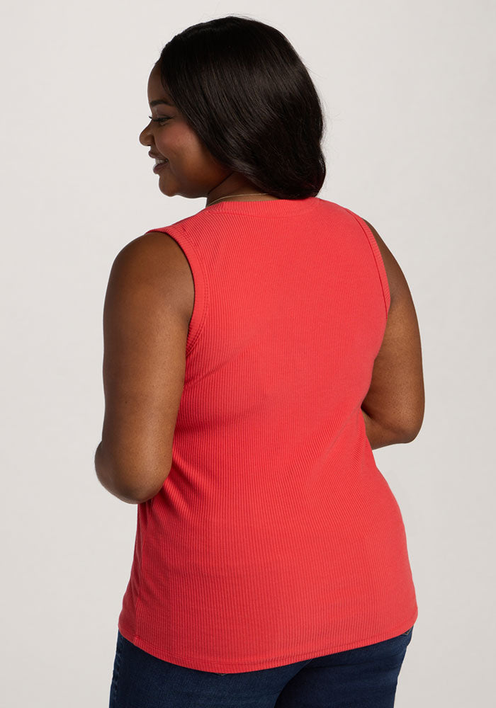 Woman with dark hair wears the Woolx Sloane Ribbed Tank in Hibiscus and blue jeans, facing away with a slight smile.