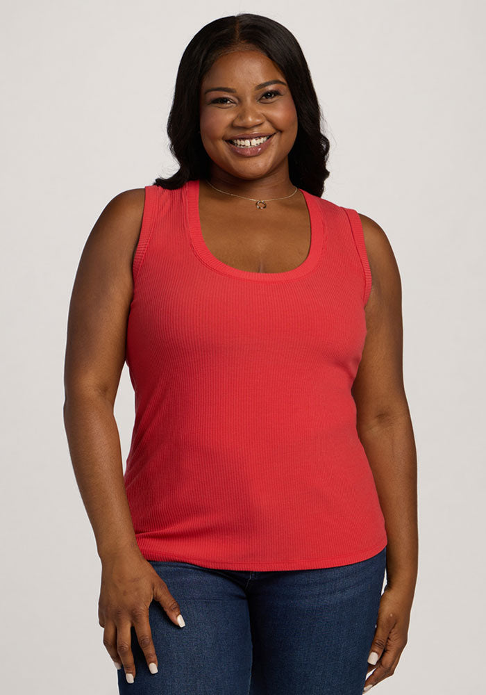 Smiling woman wears the Woolx Sloane Ribbed Tank in Hibiscus and jeans, standing against a light background. | Sapphire is 5’8”, wearing a size XL