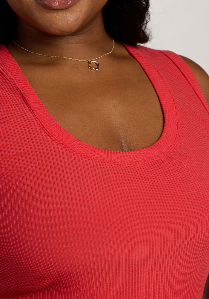 Woman wearing the Woolx Sloane Ribbed Tank in Hibiscus and a gold necklace, smiling with part of her face visible.