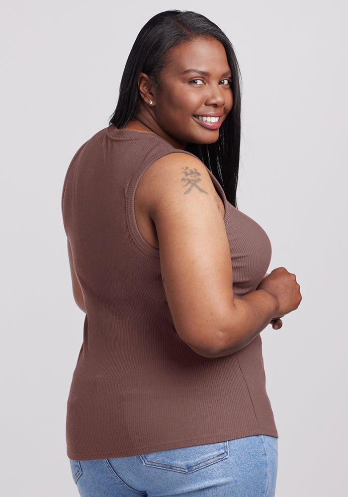 Smiling woman in the Woolx Sloane Ribbed Tank – Peppercorn and jeans, showing a tattoo on her upper arm.