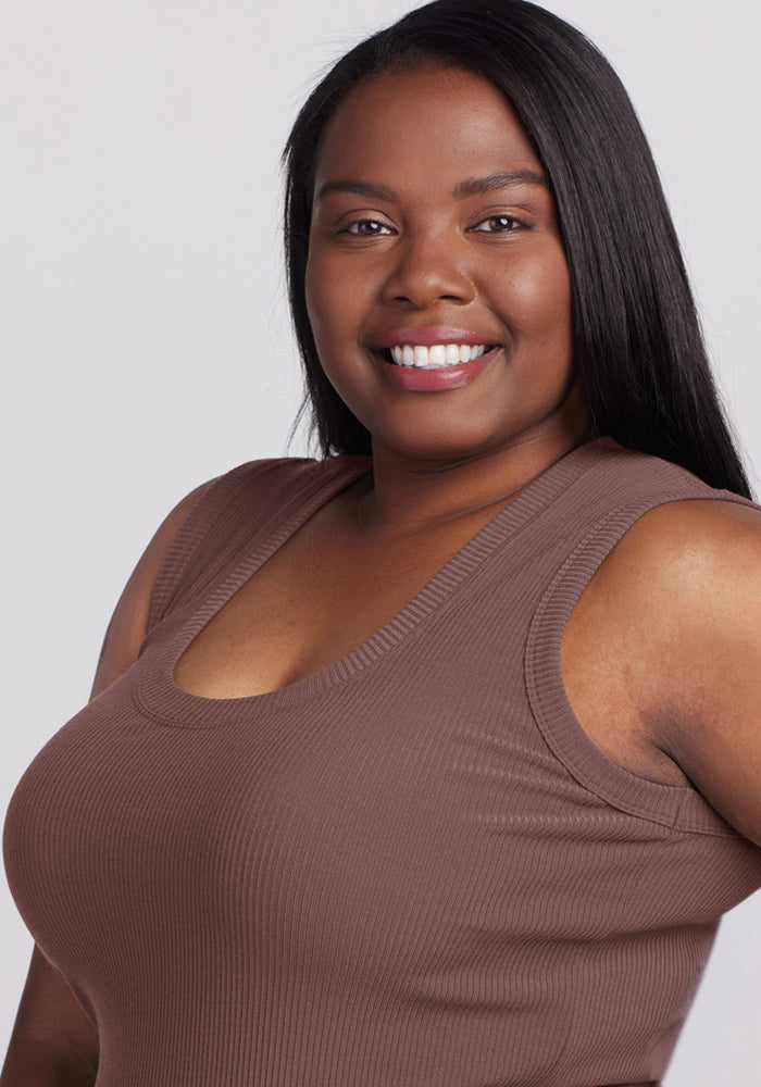 Woman with long straight hair wears the Woolx Sloane Ribbed Tank in Peppercorn, smiling at the camera on a gray backdrop.