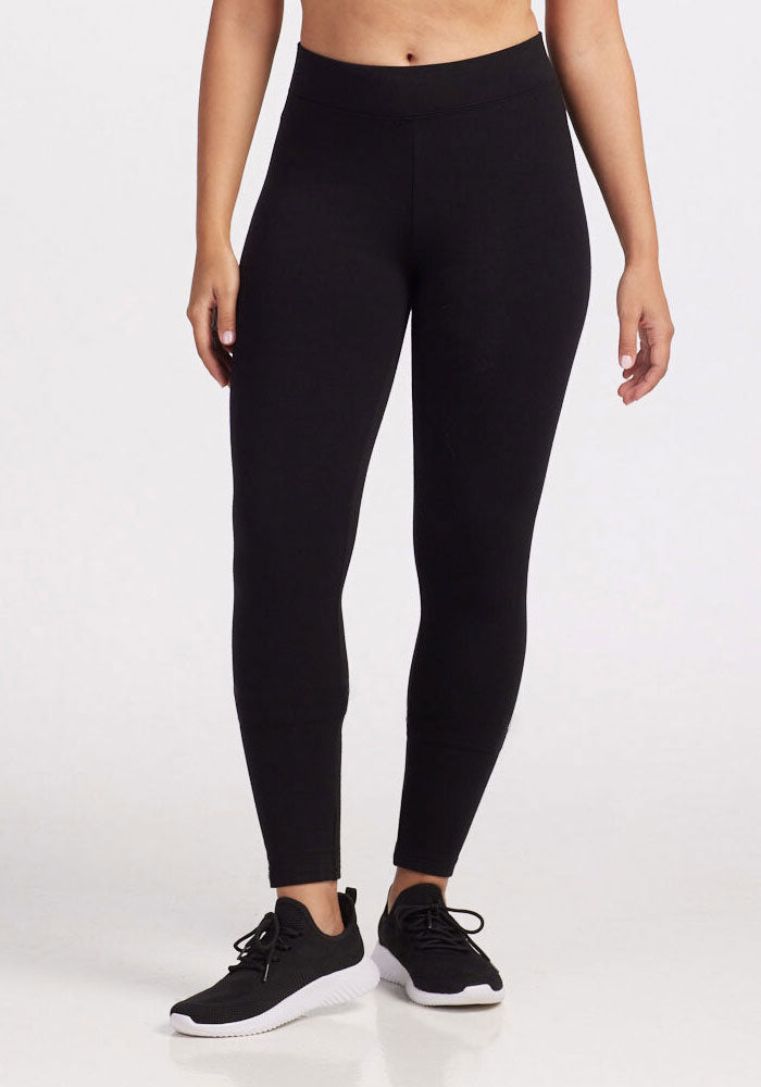 A person wearing Woolx's Stella Leggings in black along with black sneakers stands against a plain white backdrop. The outfit is casual and athletic, ideal for exercise or leisure activities during the chilly months. | Tori is 5'7", wearing a size S