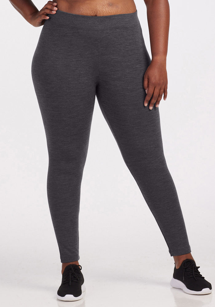 A person wearing Woolx Stella Leggings in Cinder Melange and black sneakers stands against a plain white background, with one hand on their hip. | Le’Quita is 5’11”, wearing a size XL