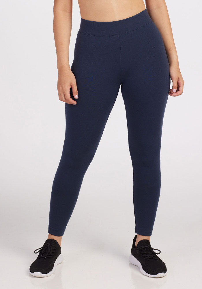 A person wearing Woolx Stella Petite leggings in Deep Navy (Final Sale Deals!), shown from mid-torso to feet with black athletic shoes, stands against a plain light background.
