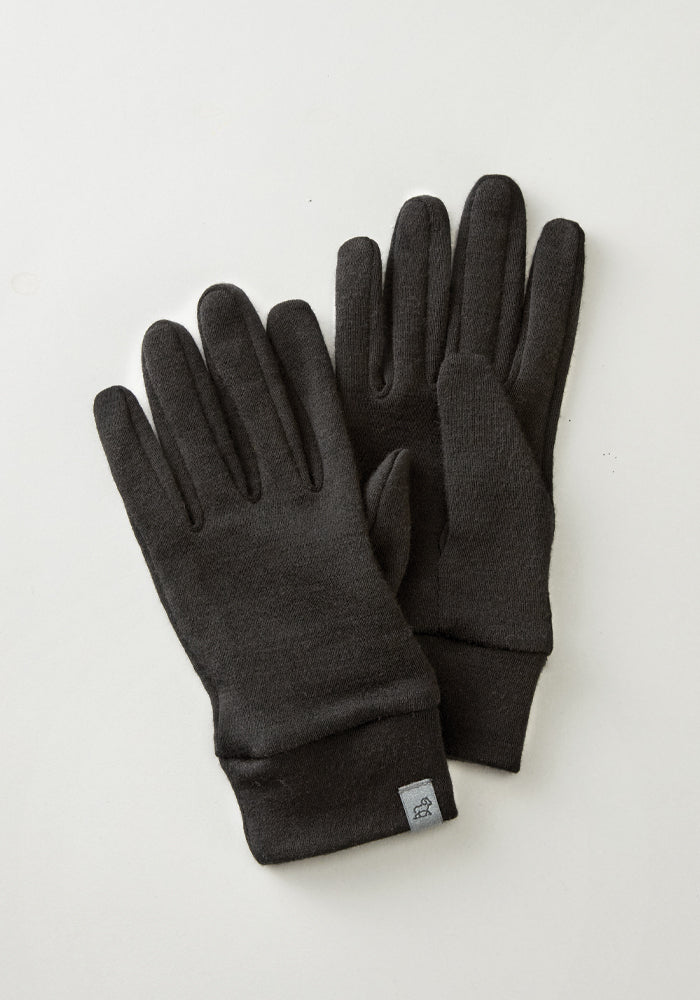 The Stone Harbor Gloves by Woolx, in black merino wool, feature a small logo tag on the left glove and are placed on a light grey background, making them perfect for winter activities.