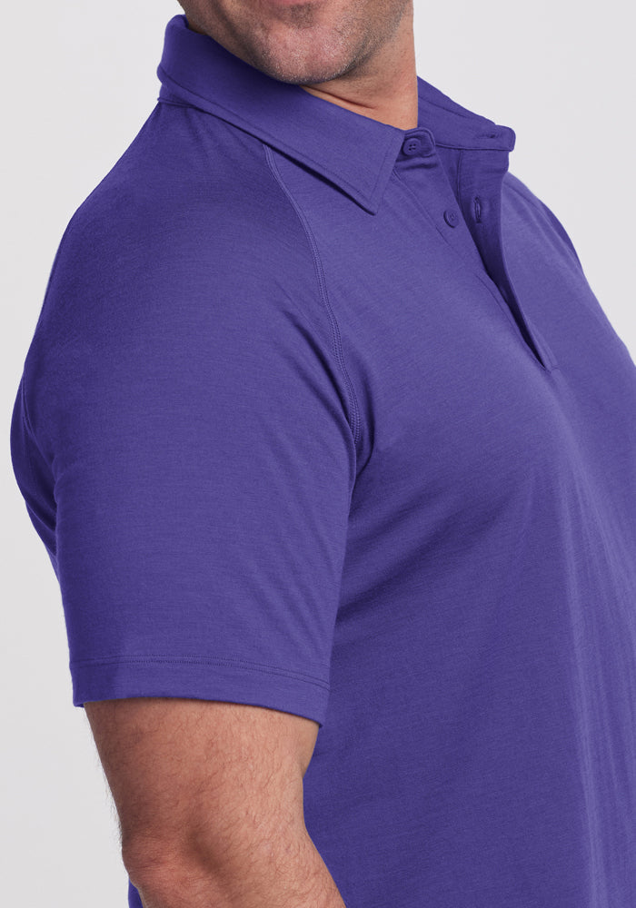 A man wears the Woolx Summit Polo - Berry Indigo, short-sleeve, shown from shoulders to mid-arm on a plain background.