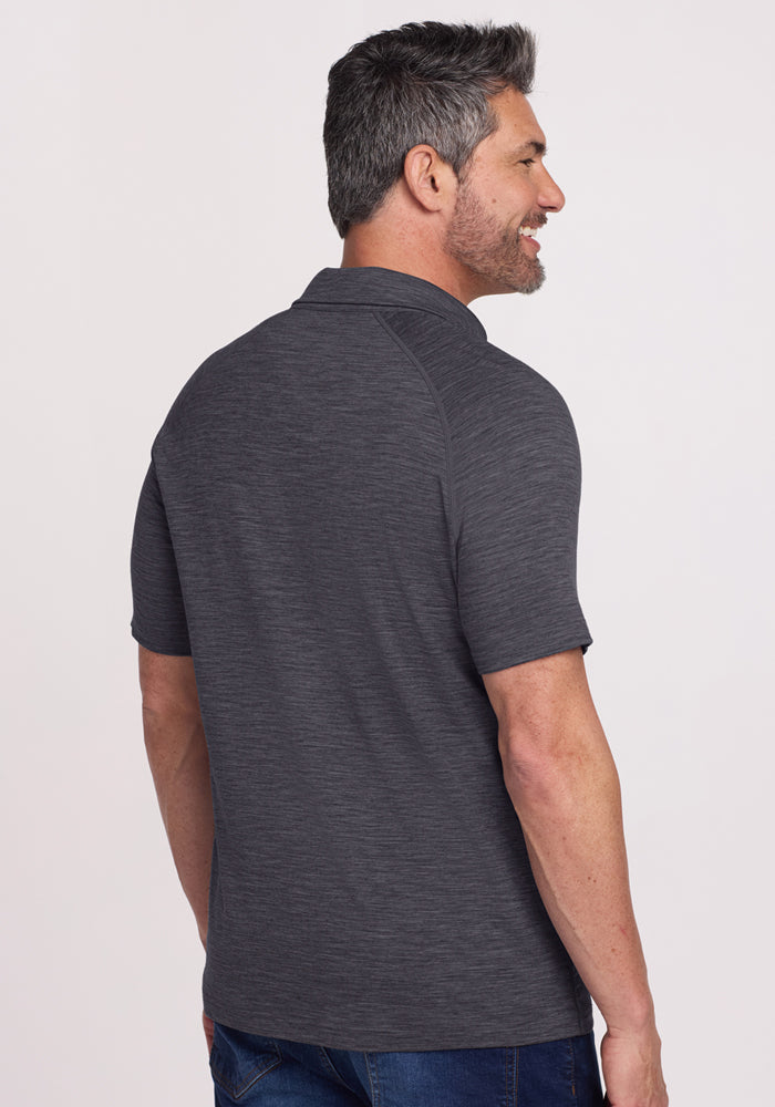 Man with short gray hair wearing the Woolx Summit Polo in Cinder Melange, standing and smiling, seen from the back.