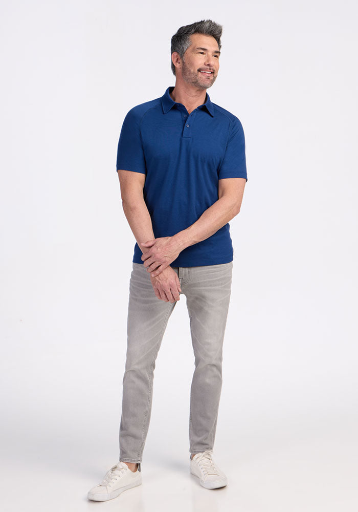 Man in a Woolx Summit Polo in Estate Blue stands smiling against a white background.