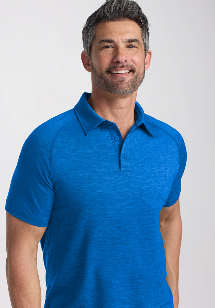 Smiling man with short dark hair and beard wears the Woolx Summit Polo in Glacial Blue, known for moisture management.
