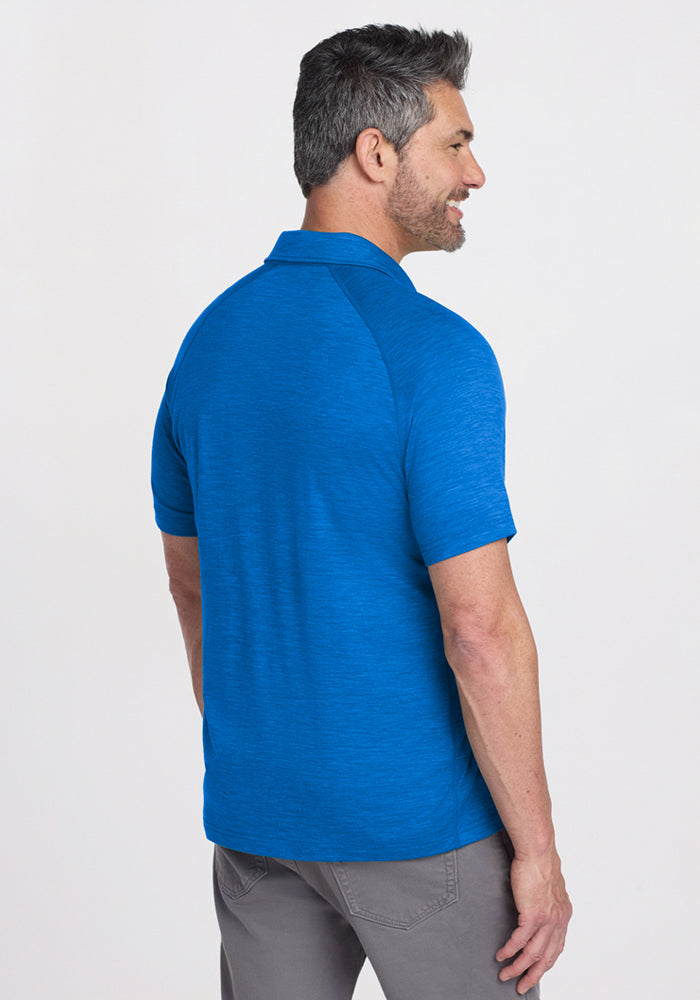 Man with short dark hair in a Woolx Summit Polo • Final Sale - Glacial Blue and gray pants, facing away and smiling.