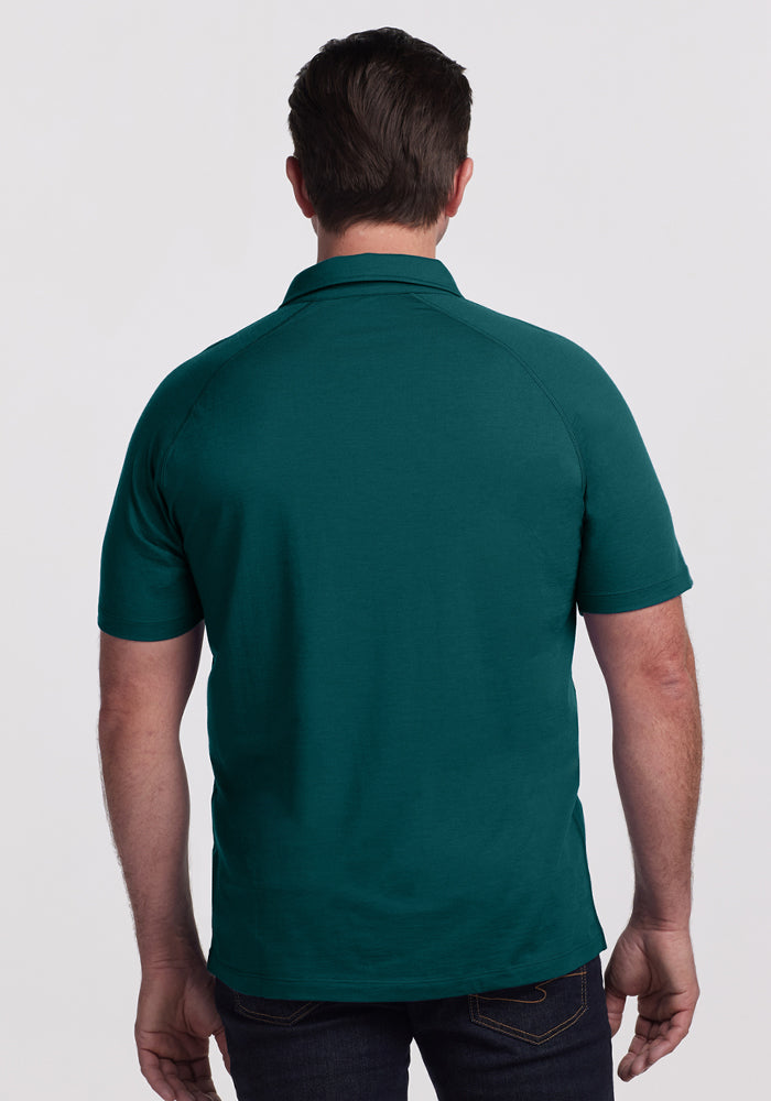 A man in a Woolx Summit Polo • Final Sale - Riverbank Green and dark jeans, shown from the back against a plain background.