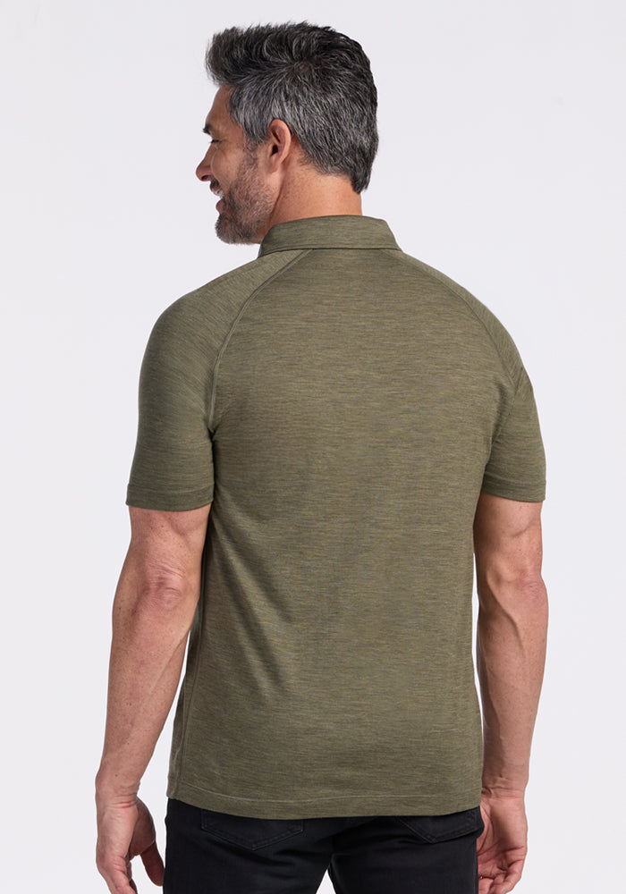 Man with short gray hair wears Woolx Summit Polo in Sage Olive Melange, black pants, back view on white background.