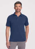 Man wears Woolx Summit Polo in Starry Night and gray pants, smiling confidently in high-performance athletic gear.