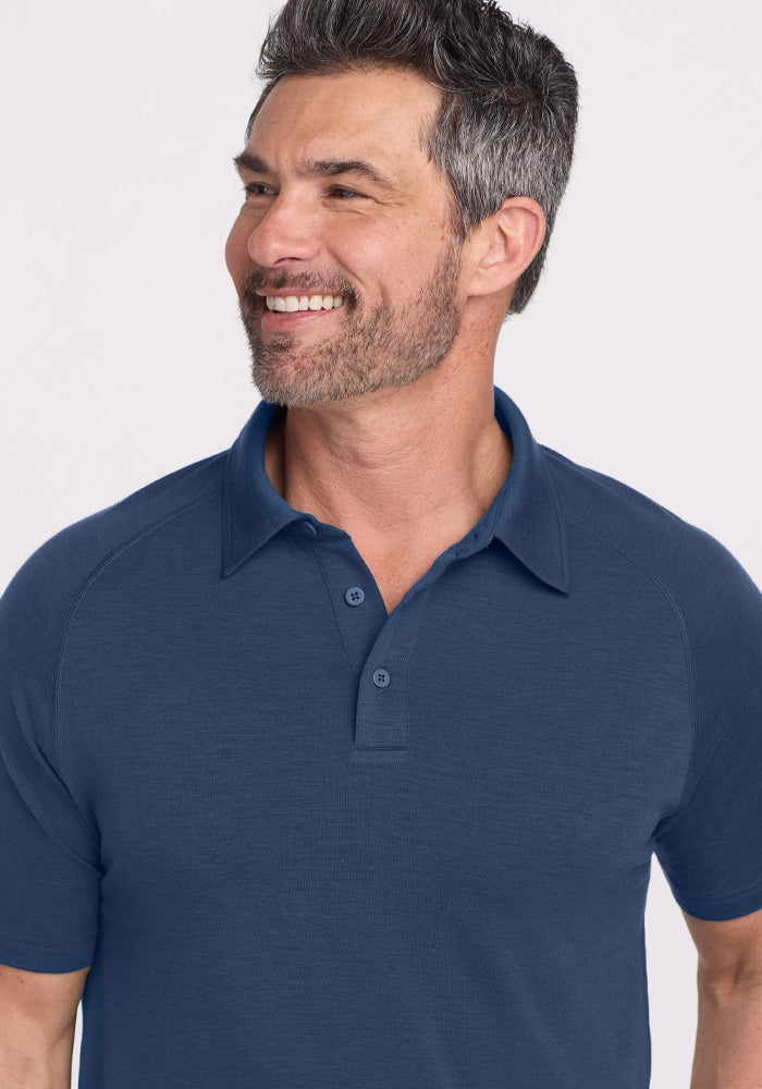 Smiling man with short dark hair and beard wearing the Woolx Summit Polo • Final Sale - Starry Night, looking aside.