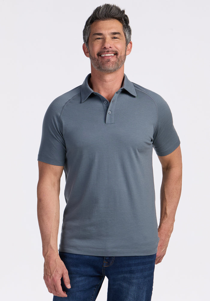 Gray-haired man in Woolx Summit Polo • Final Sale - Stormy Weather and blue jeans, against a white background.