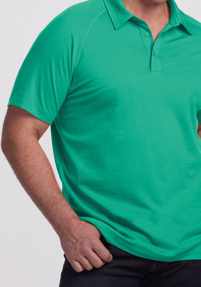 Man in a bright green Woolx Summit Polo - Jungle, Merino wool, moisture-wicking, with dark jeans and hand in pocket.