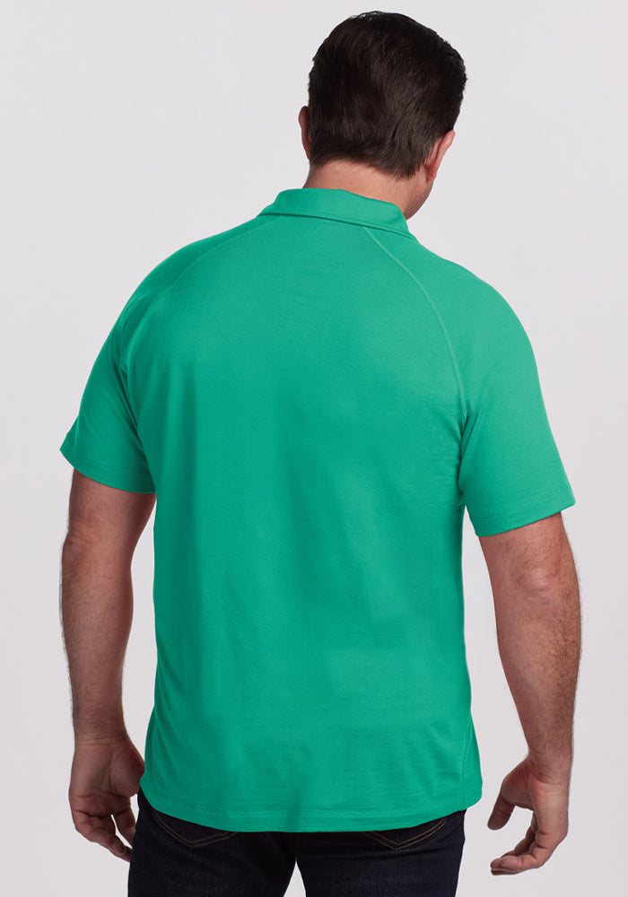 Man wears Woolx Summit Polo - Jungle, facing away to show the back, collar, and moisture-wicking fabric.