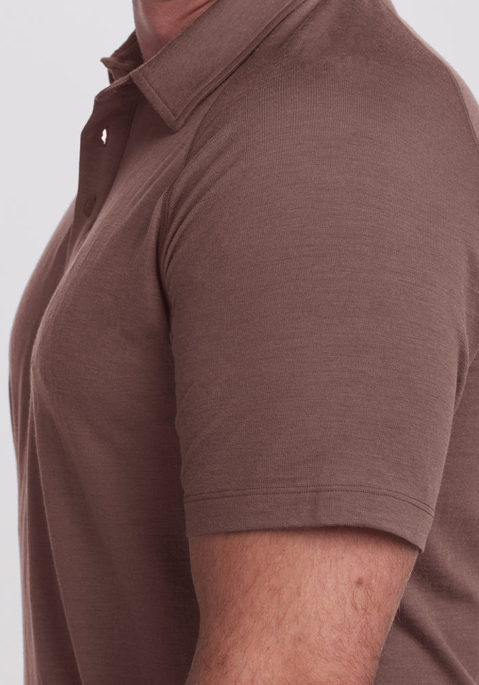 A person in a Woolx Summit Polo - Peppercorn, brown Merino wool, shown from the side, upper body only.