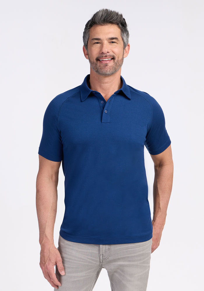 Man with short gray hair and beard wearing a Woolx Summit Polo in Estate Blue and gray jeans, smiling at the camera.