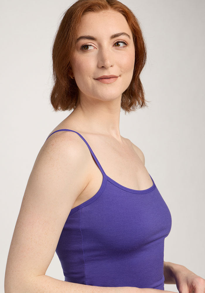 A woman with short red hair smiles softly, wearing the Woolx Teagen Cami With Shelf Bra in Berry Indigo.