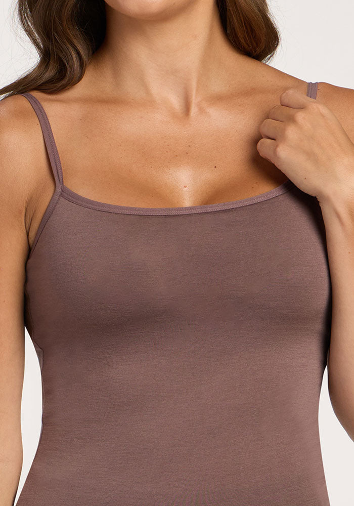Woman wears a peppercorn Woolx Teagen cami with shelf bra, hand touching one spaghetti strap.