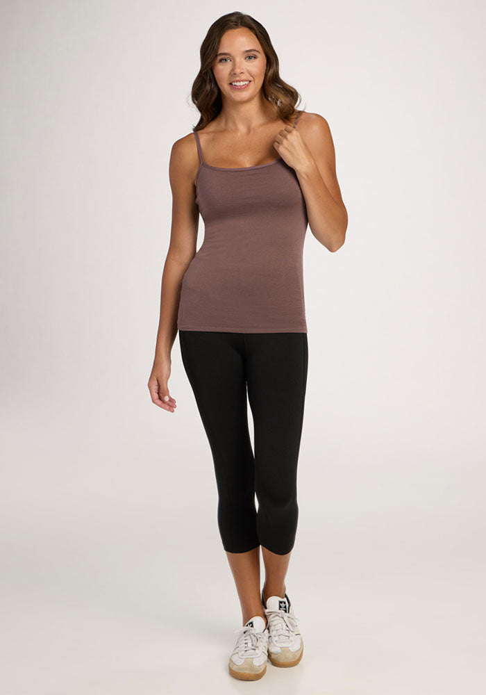 Woman standing and smiling in a Woolx Teagen Cami With Shelf Bra in Peppercorn, black leggings, and white sneakers.