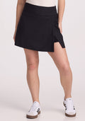 A person wearing the Topanga Skort - Black from Woolx and white sneakers stands against a plain white background. | Ariana is 5’11”, wearing a size S