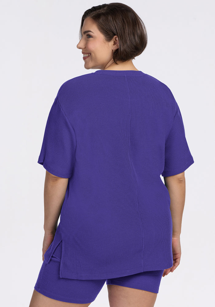 A woman in the Woolx Vera Ribbed Tunic in Berry Indigo, smiling and facing away from the camera.