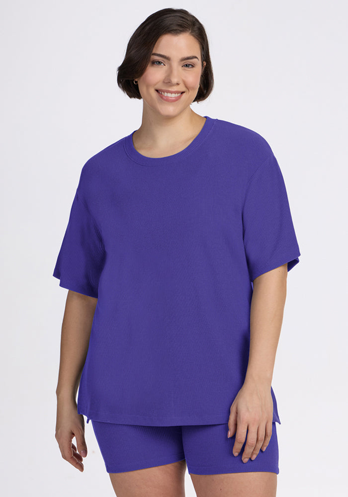 A woman smiles in the Woolx Vera Ribbed Tunic in Berry Indigo with matching shorts against a plain light background. | Juliana is 5'10", wearing a size XL