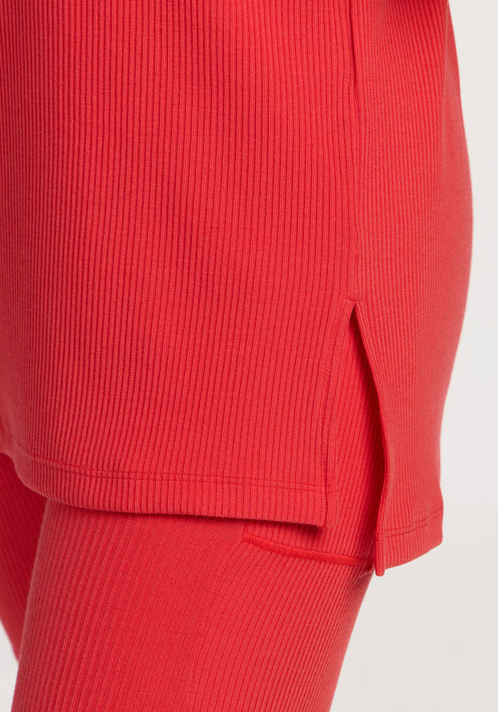 Close-up of the Woolx Vera Ribbed Tunic in Hibiscus, tunic length with side slit, over matching ribbed leggings.