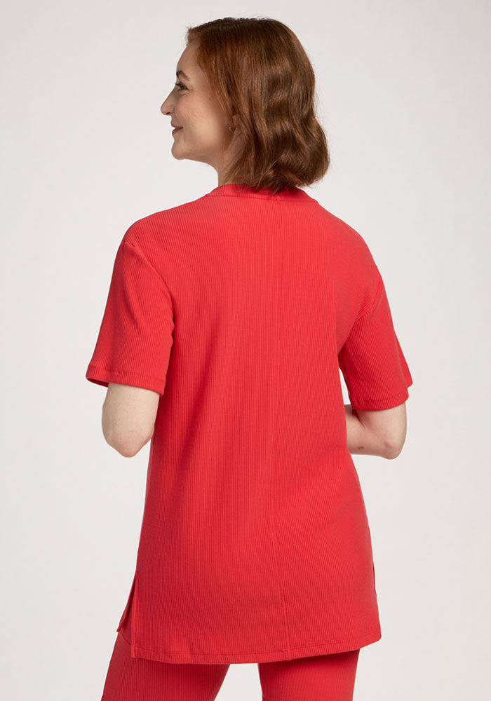 Woman with short brown hair wears the Woolx Vera Ribbed Tunic in Hibiscus, seen from the back.