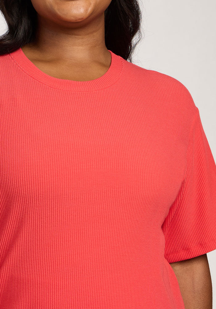 A person wearing the Woolx Vera Ribbed Tunic in Hibiscus, shown from shoulder to below the chin.