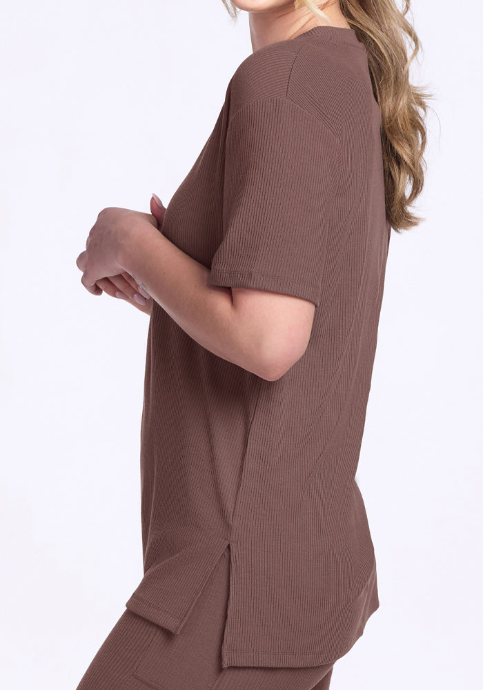 Woman in the Woolx Vera Ribbed Tunic in Peppercorn, relaxed fit merino wool with short sleeves and side slits, side view.
