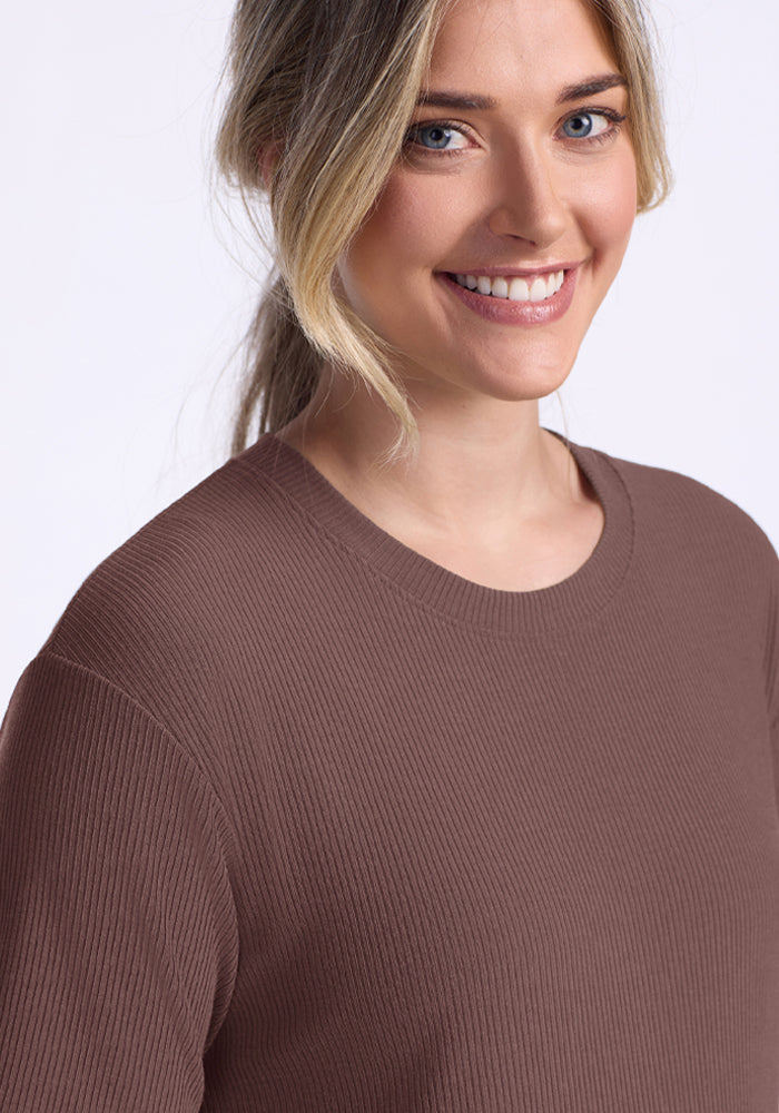A smiling woman with a ponytail wears the Woolx Vera Ribbed Tunic in Peppercorn against a light background.
