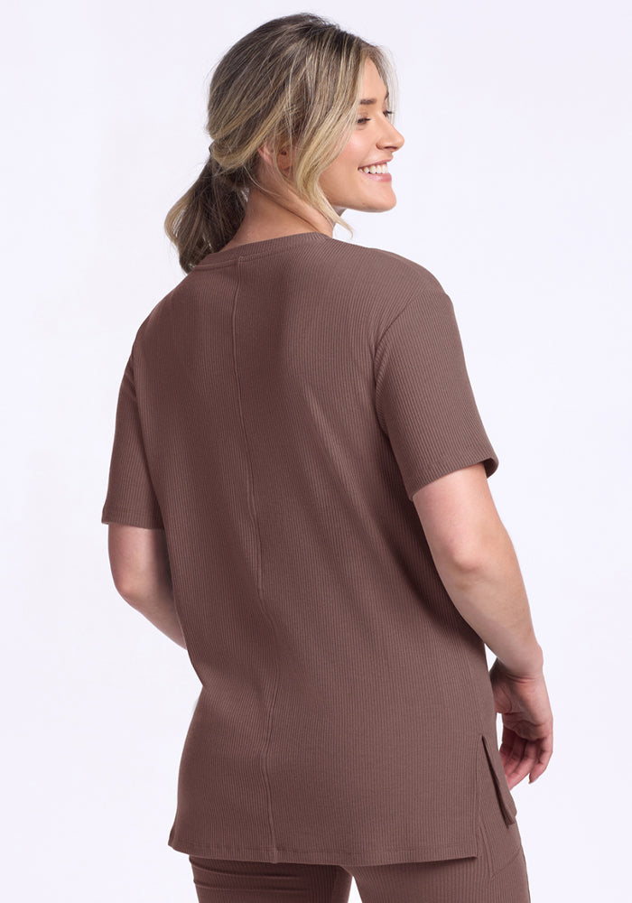 Blonde woman smiles over her shoulder, wearing the Woolx Vera Ribbed Tunic in Peppercorn.