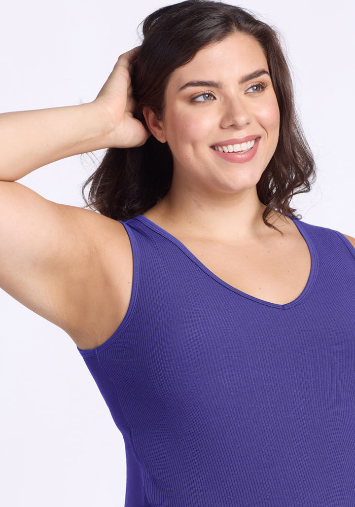 Woman with wavy brown hair smiles in the Woolx Vivi Ribbed Tank - Berry Indigo, hand behind her head.