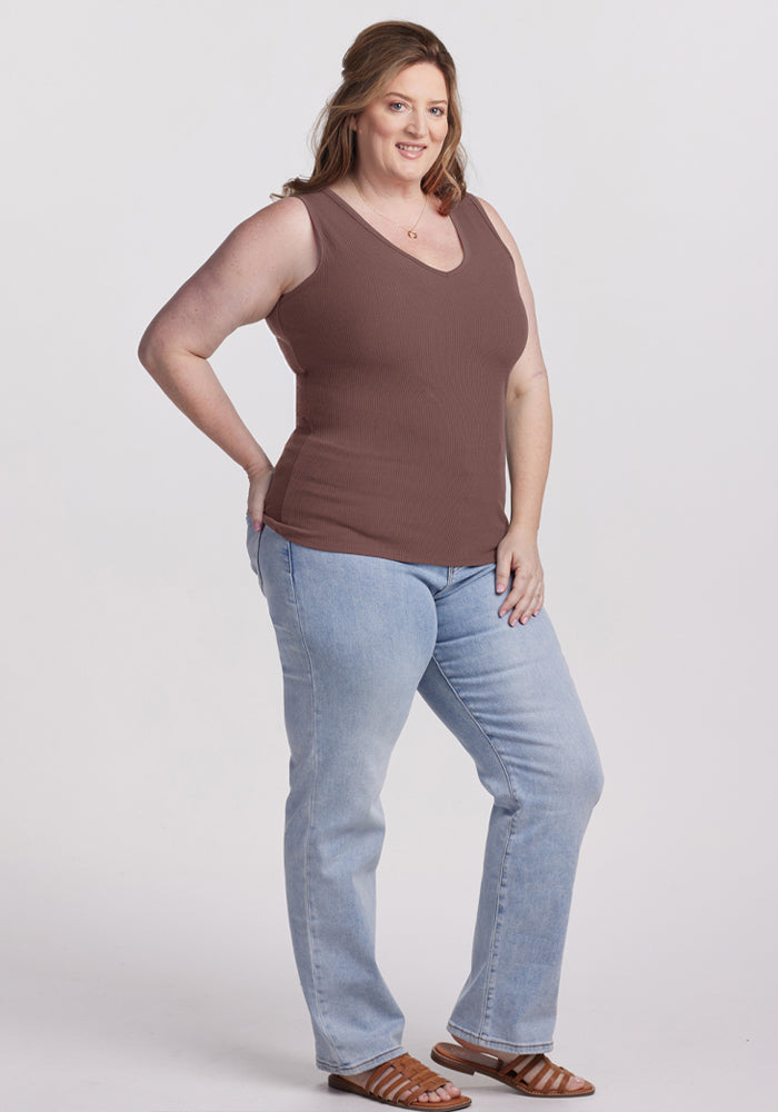 Smiling woman in the Woolx Vivi Ribbed Tank - Peppercorn, light blue jeans, and brown sandals poses against a white background.