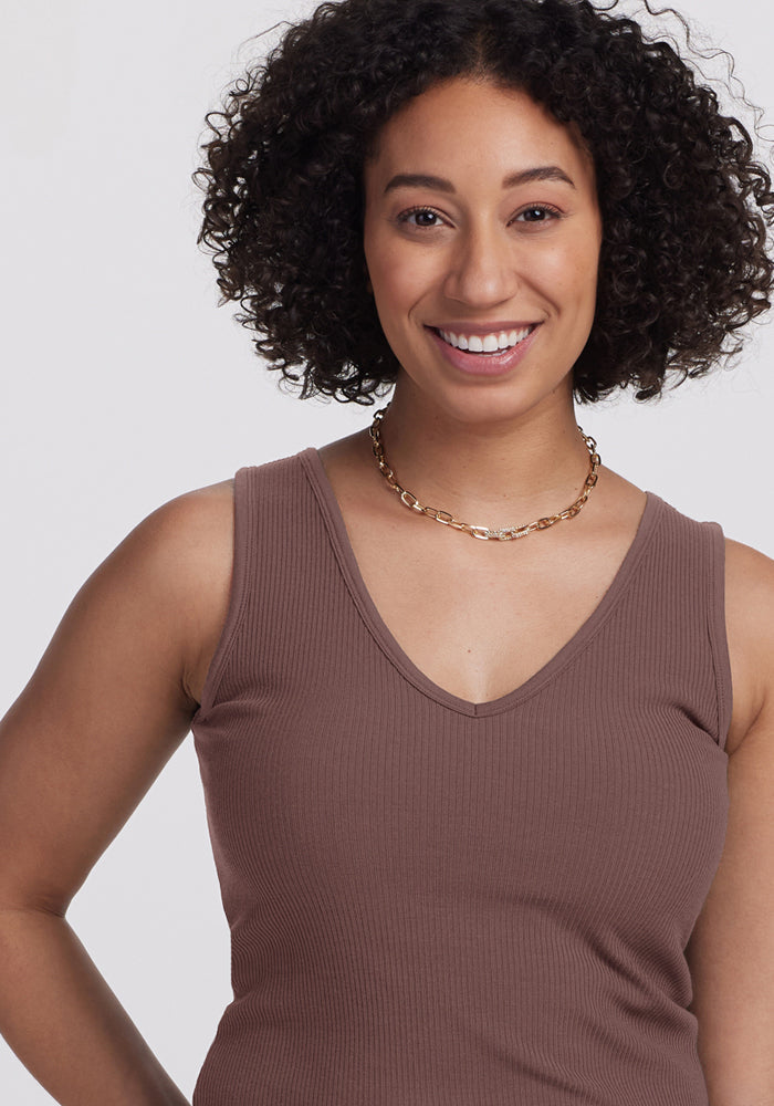 Smiling woman with curly hair wears the Woolx Vivi Ribbed Tank in Peppercorn and a gold chain necklace.