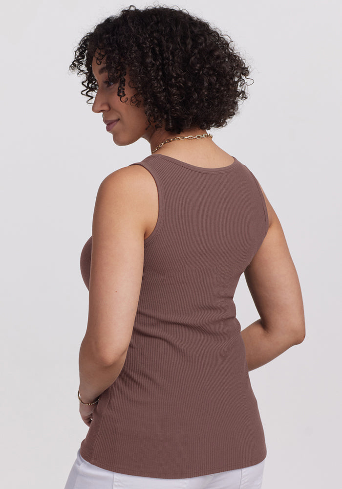 A woman with curly hair, shown from the back, wears the Woolx Vivi Ribbed Tank in Peppercorn and white pants.