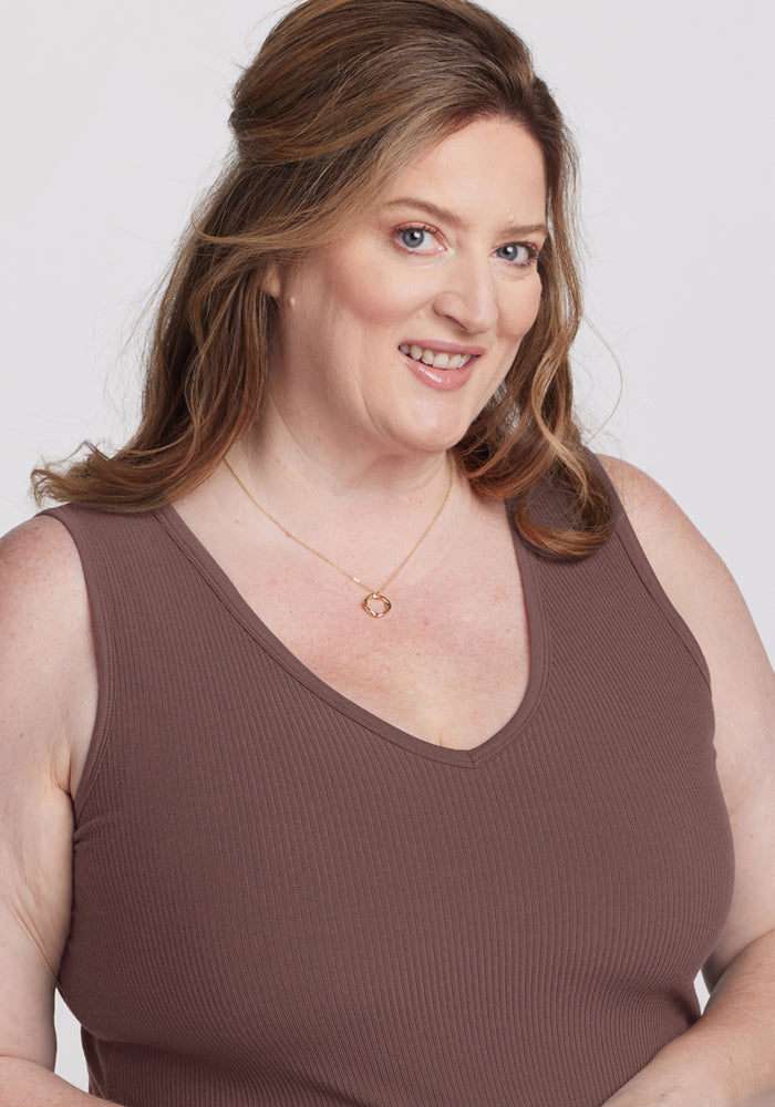 Smiling woman in the Woolx Vivi Ribbed Tank - Peppercorn, with wavy brown hair and a gold necklace, against a light background.