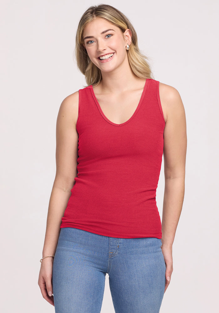 Smiling woman in the Woolx Vivi Ribbed Tank - Berry Ice Pop and blue jeans, standing against a plain background. | Ariana is 5'11", wearing a size S