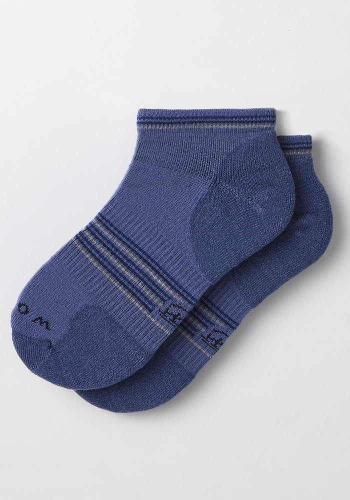 A pair of Woolx Womens Amelia No Show Socks in Skyline, featuring blue moisture-wicking fabric with thin lighter stripes and darker accents on the toe and heel, laid flat on a white surface.
