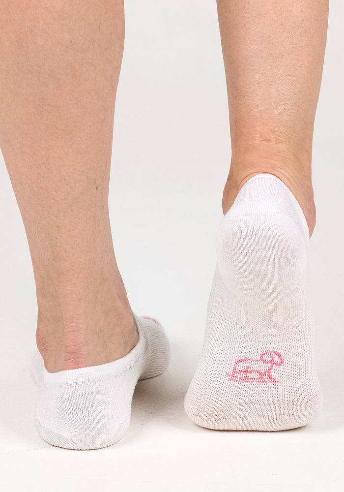A close-up of two feet wearing Woolx Womens Daisy Ped Socks - White Lightning. The right sock displays a small pink logo on the sole. The background is plain white.