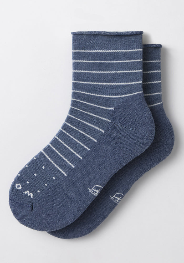 The Woolx Womens Derby Roll Top Sock in Vintage Indigo features white horizontal stripes and dotted toes, displayed on a plain light background. These lightweight, comfortable socks are ideal for everyday wear.