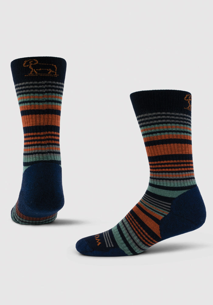 Introducing the Everyday Light Cushion Crew Socks - Deep Navy Stripe by Woolx: a vibrant pair of merino wool socks showcasing navy, green, gray, and orange stripes. These temperature-regulating socks feature a reinforced toe and heel in navy and an embroidered running dog design near the top band. Displayed individually, one sock stands upright while the other lies flat.