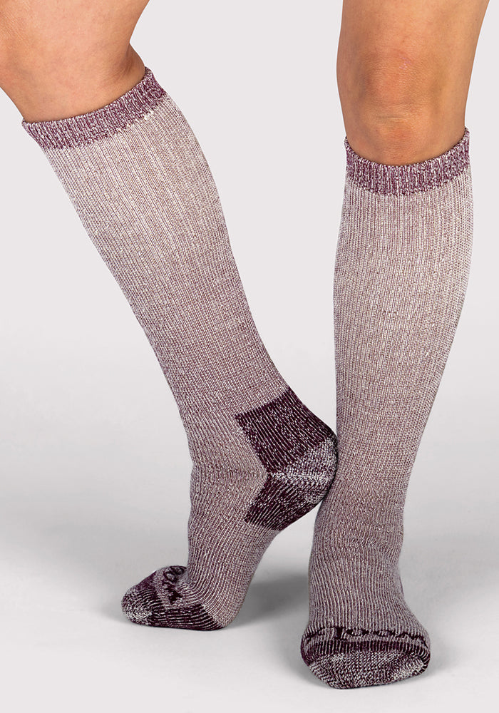 Two legs wear Woolx Womens Extreme Over The Calf Socks in Windsor Wine—a heathered purple with darker toe, heel, and cuff—standing on a neutral background. Perfect for warmth and coziness all winter long.