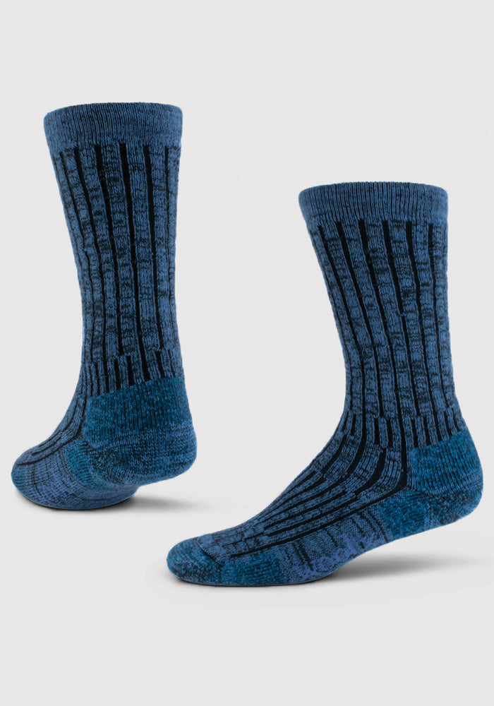 Introducing the Joey Full Cushion Mid Calf Socks from Woolx in Steel Blue. These socks feature black vertical stripes and a textured pattern, crafted from soft merino wool. They are presented against a light gray backdrop, standing upright to highlight their full length and design.