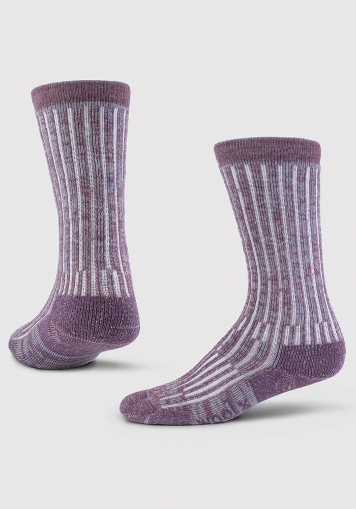 A pair of Joey Socks - Wildflower by Woolx, made from high-quality Australian Merino Wool, is displayed against a white background. One sock stands upright while the other is propped up at an angle. The design features vertical stripes in alternating purple and white.