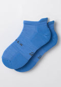 The Woolx Womens Rowan No Show Socks - Wave Rider are blue cushioned ankle socks with ribbed cuffs and a textured pattern, shown overlapping on a white background with small black text and symbols.